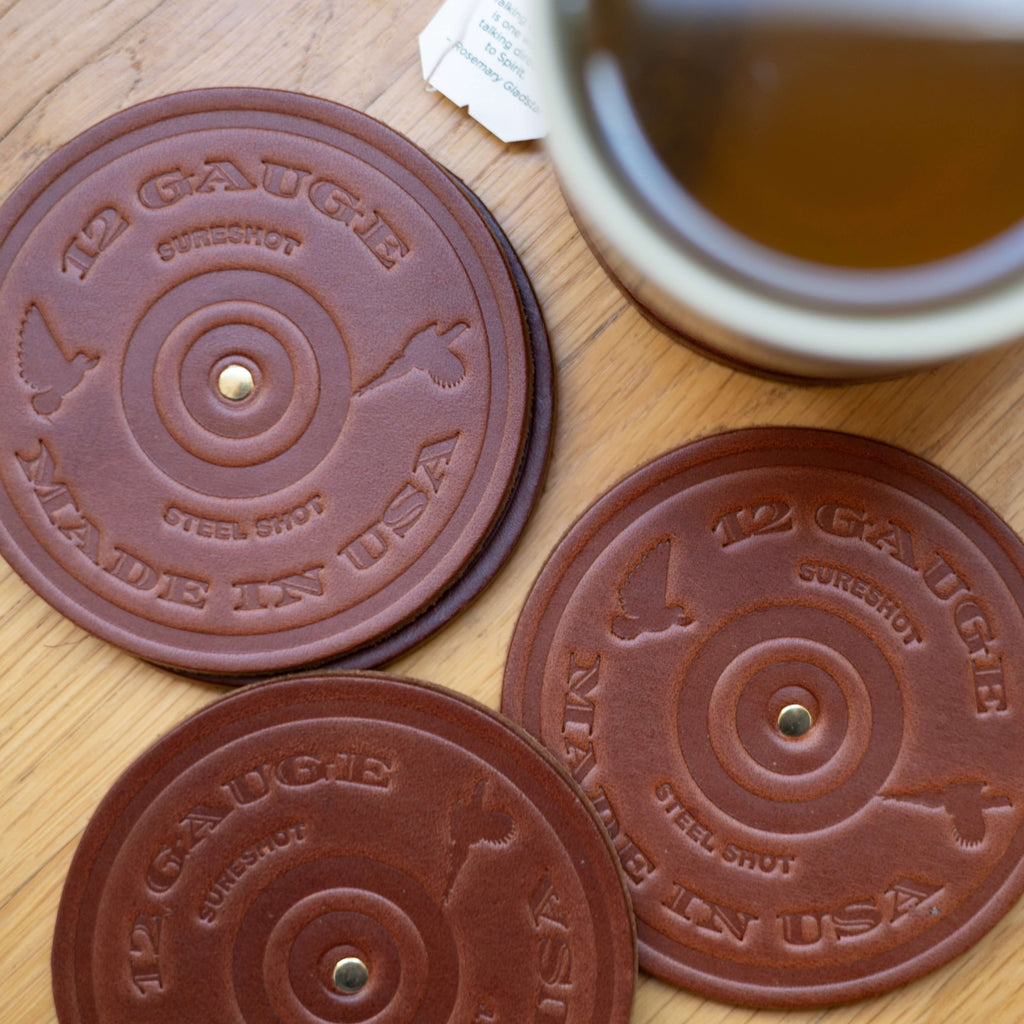 Three brown round custom logo coasters with 'Made in USA' text on a wooden surface with a mug of tea.